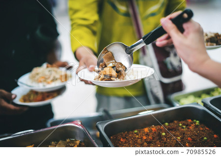 Homeless people receive free charity food from the hands of volunteers 70985526