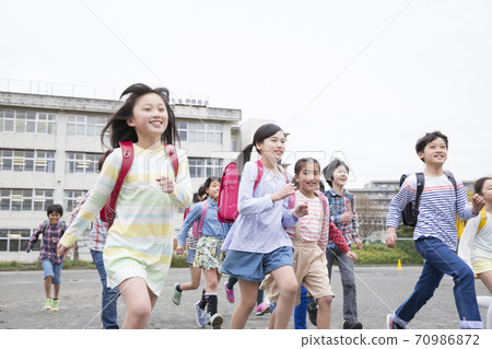 Elementary school students running in the schoolyard 70986872