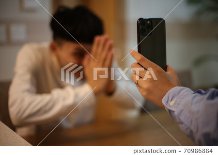 Woman showing smartphone screen to man Woman showing smartphone screen to man 70986884