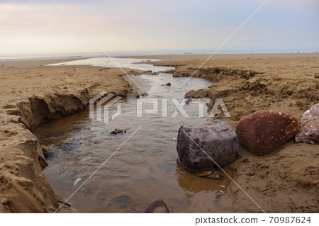 Flowing Water Into The Sea With Interesting Stones 70987624