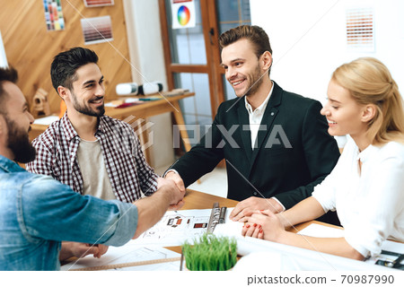 People shake hands at a table in the office. People shake hands at a table in the office. 70987990