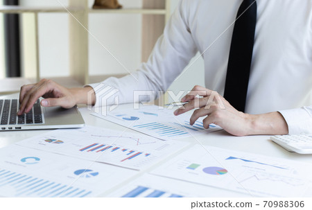 Financial businessmen use laptop to analyze marketing strategies and real estate data to reduce company taxes for their customers, Accounting and Tax concept. Financial businessmen use laptop to analyze marketing strategies and real estate data to reduce company taxes for their customers, Accounting and Tax concept. 70988306