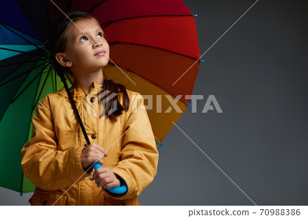 Cheerful child girl with umbrella on gray background. Cheerful child girl with umbrella on gray background. 70988386