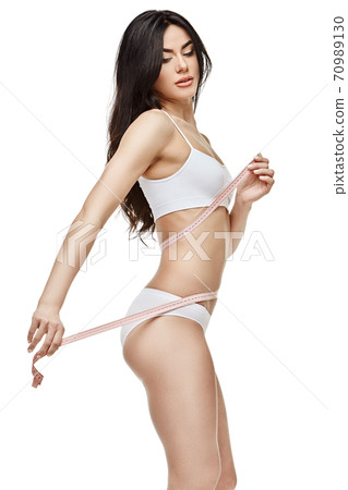 Slim tanned woman's body isolated on white background - waist measurement 70989130