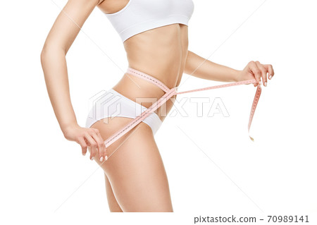 Slim tanned woman's body isolated on white background - waist measurement 70989141