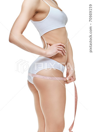 Slim tanned woman's body isolated on white background - waist measurement 70989159