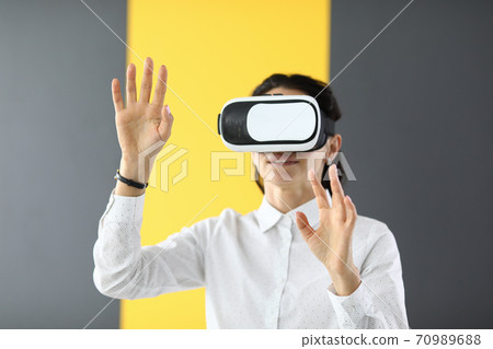 Young woman touches air with her hands in virtual reality glasses Young woman touches air with her hands in virtual reality glasses 70989688