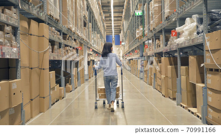 Asian woman working or shopping on shelves at large warehouse retail store industry. Rack of furniture and home accessories store. Interior of cargo in ecommerce and logistic concept. Lifestyle Asian woman working or shopping on shelves at large warehouse retail store industry. Rack of furniture and home accessories store. Interior of cargo in ecommerce and logistic concept. Lifestyle 70991166