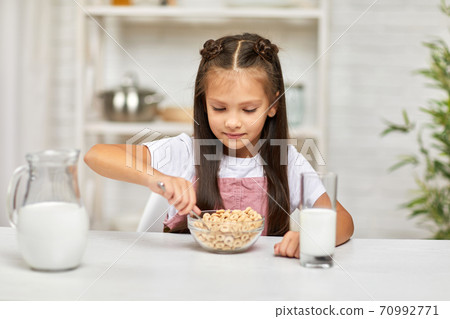 cute little girl eating breakfast: cereal with the milk cute little girl eating breakfast: cereal with the milk 70992771