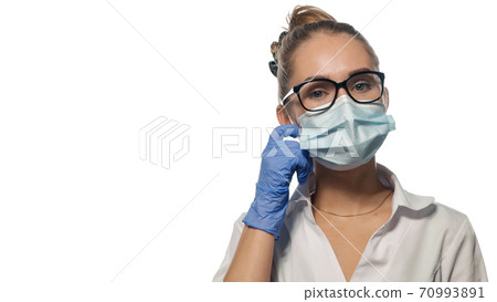 Young doctor fixing her mask. Young doctor fixing her mask. 70993891