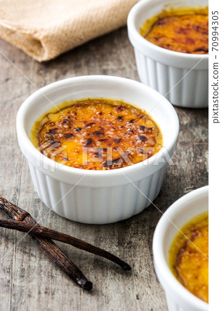 Traditional French creme brulee dessert with caramelized sugar on top, on wooden table	 70994305