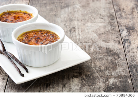 Traditional French creme brulee dessert with caramelized sugar on top, on wooden table	 70994306