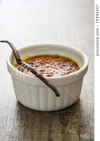 Traditional French creme brulee dessert with caramelized sugar on top, on wooden table	 70994307