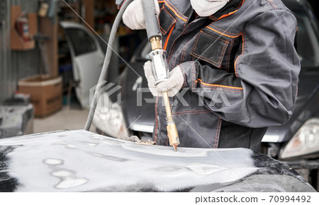 Spotter, a Welding machine for straightening dents on the car body. spot welding of metal. Repair service worker fix damaged car. Spotter, a Welding machine for straightening dents on the car body. spot welding of metal. Repair service worker fix damaged car. 70994492