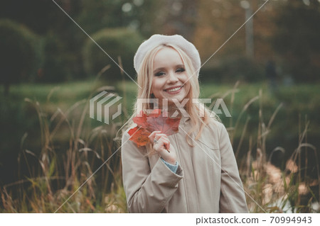 Smiling autumn woman holding autumn leaves on fall nature background 70994943