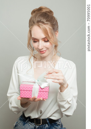 Cheerful woman holding pink gift on white background 70995001