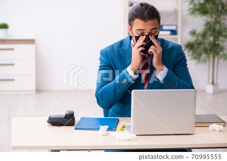 Sick male employee suffering at workplace from coronavirus Sick male employee suffering at workplace from coronavirus 70995555