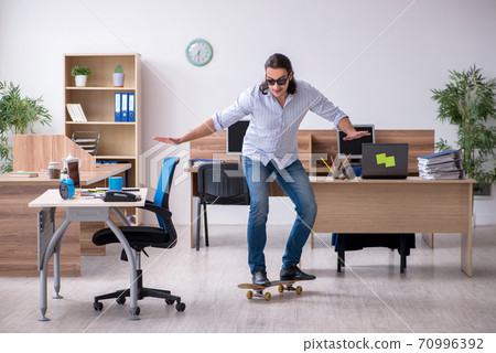 Young male employee with skateboard in the office 70996392