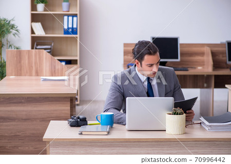 Young male employee working in the office 70996442