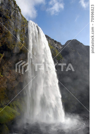 Seljalandsfoss Waterfall in Iceland. A famous waterfall with a path to walk behind the falls. Seljalandsfoss Waterfall in Iceland. A famous waterfall with a path to walk behind the falls. 70996823