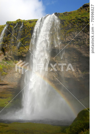 Seljalandsfoss Waterfall in Iceland. A famous waterfall with a path to walk behind the falls. Seljalandsfoss Waterfall in Iceland. A famous waterfall with a path to walk behind the falls. 70996827