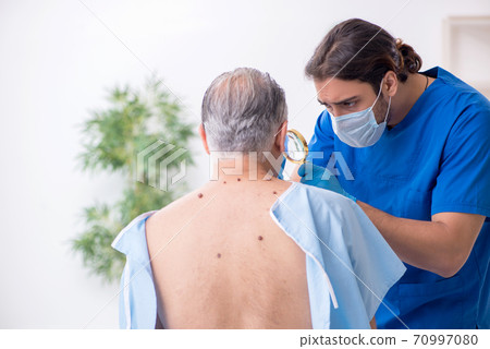 Old man visiting young male doctor dermatologist 70997080