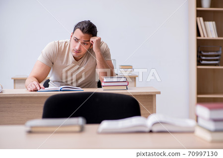 Young male student preparing for exams at library Young male student preparing for exams at library 70997130