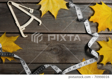 Autumn fallen leaves, measuring tape and caliper on wooden background. 70998016