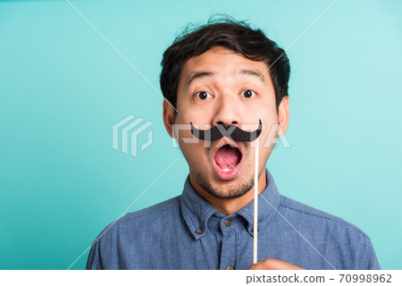 handsome man holding funny mustache card on his mouth 70998962