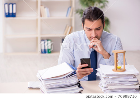 Young male employee in time management concept Young male employee in time management concept 70999710