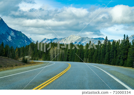 Rural road in the forest with mountains in the background. Alberta Highway 11 (David Thompson Hwy), Jasper National Park, Canada. Rural road in the forest with mountains in the background. Alberta Highway 11 (David Thompson Hwy), Jasper National Park, Canada. 71000334
