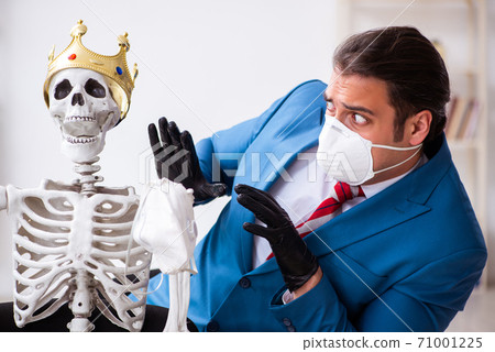 Young businessman and skeleton in the office in pandemic concept Young businessman and skeleton in the office in pandemic concept 71001225