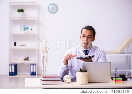 Young male doctor reading book in the clinic 71001899
