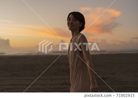 A woman walking along the beach 71002915