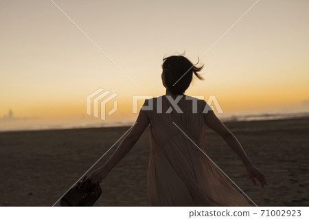 A woman walking along the beach 71002923