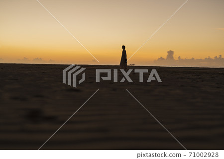 A woman walking along the beach 71002928