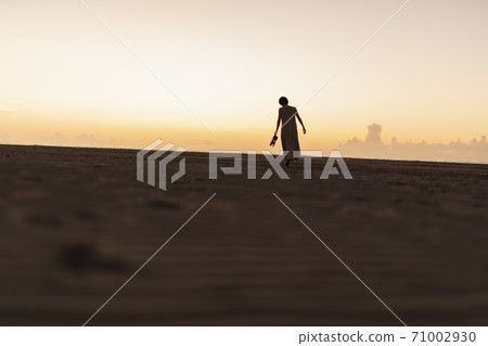 A woman walking along the beach 71002930