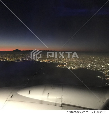 Mt. Fuji silhouette after the sun goes down as seen from the window of an airplane flying in the night sky Mt. Fuji silhouette after the sun goes down as seen from the window of an airplane flying in the night sky 71003498