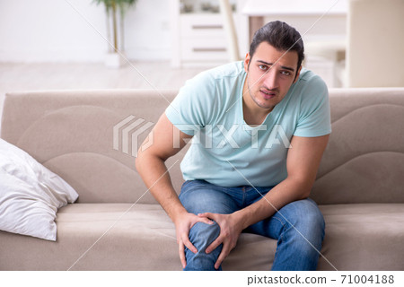 Injured young man suffering at home Injured young man suffering at home 71004188