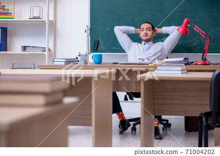 Young male teacher in front of green board Young male teacher in front of green board 71004202