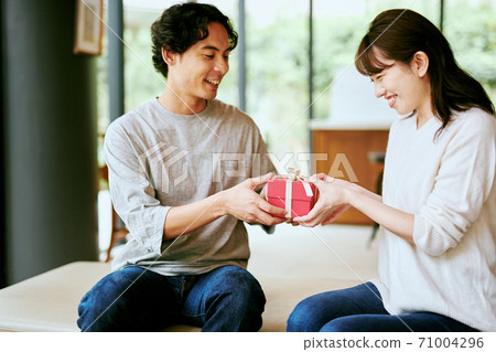 A man giving a gift to a woman A man giving a gift to a woman 71004296