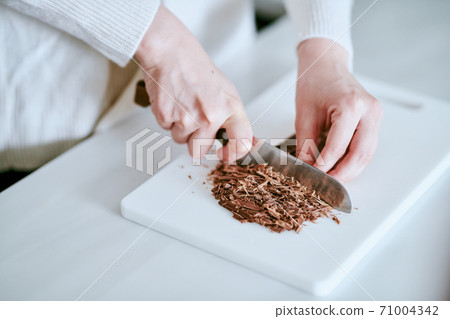 Woman cutting chocolate in the kitchen 71004342