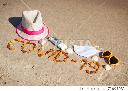 Inscription Covid-19 made of amber stones, mask, disinfectant liquid and vacation accessories Inscription Covid-19 made of amber stones, mask, disinfectant liquid and vacation accessories 71005981