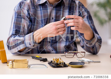 Young male watchmaker working in the workshop 71006338