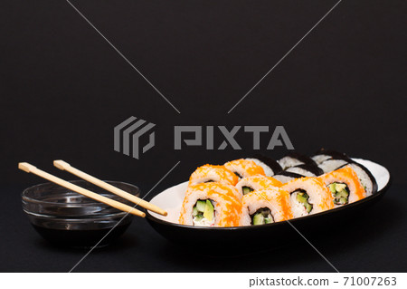 Uramaki California. Sushi rolls and bowl with soy sauce on black background. 71007263