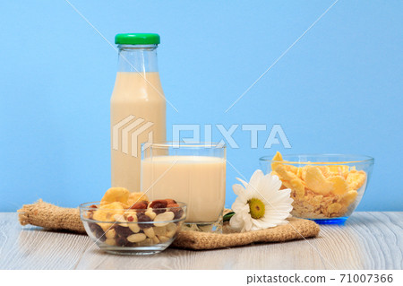 Bottle and glass of milk, bowls with muesli and cornflakes on sackcloth. Bottle and glass of milk, bowls with muesli and cornflakes on sackcloth. 71007366