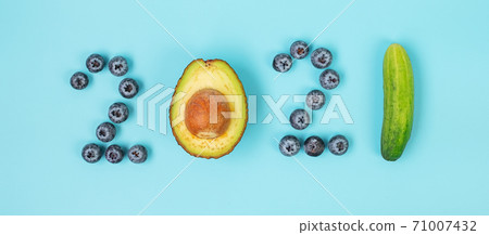 2021 Happy New Year and New You with fruits and Vegetables; Blueberries, Avocado and cucumber on blue background. Goals, Healthy, Resolution, Time to New Start and dieting concept 71007432