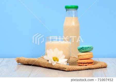 Bottle and glass of milk with macaroons in blue background. Bottle and glass of milk with macaroons in blue background. 71007452