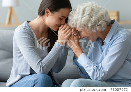 Caring young adult woman granddaughter hold hands of old grandmother Caring young adult woman granddaughter hold hands of old grandmother 71007972