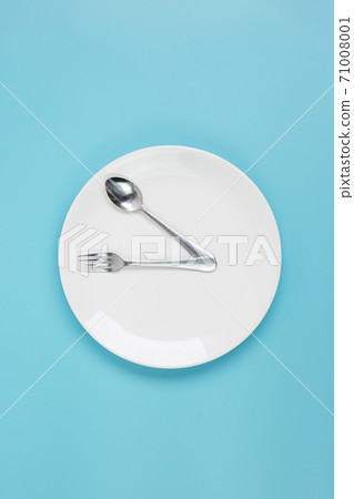 Top view white ceramic plate with knife, spoon and fork on blue background. Intermittent fasting, Ketogenic dieting, weight loss, meal plan and healthy food concept 71008001
